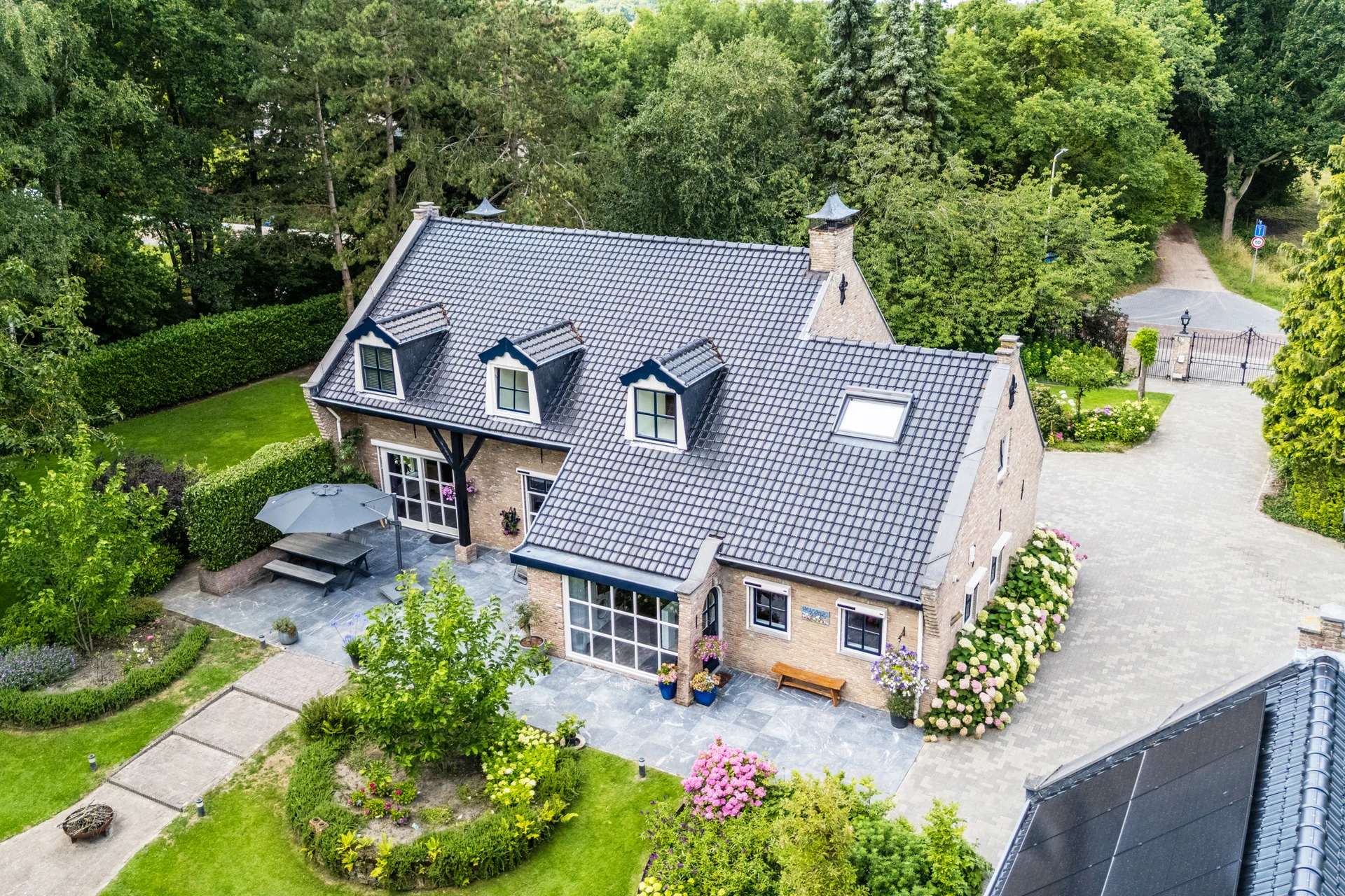 Drone photo of a detached home with garden, driveway and trees