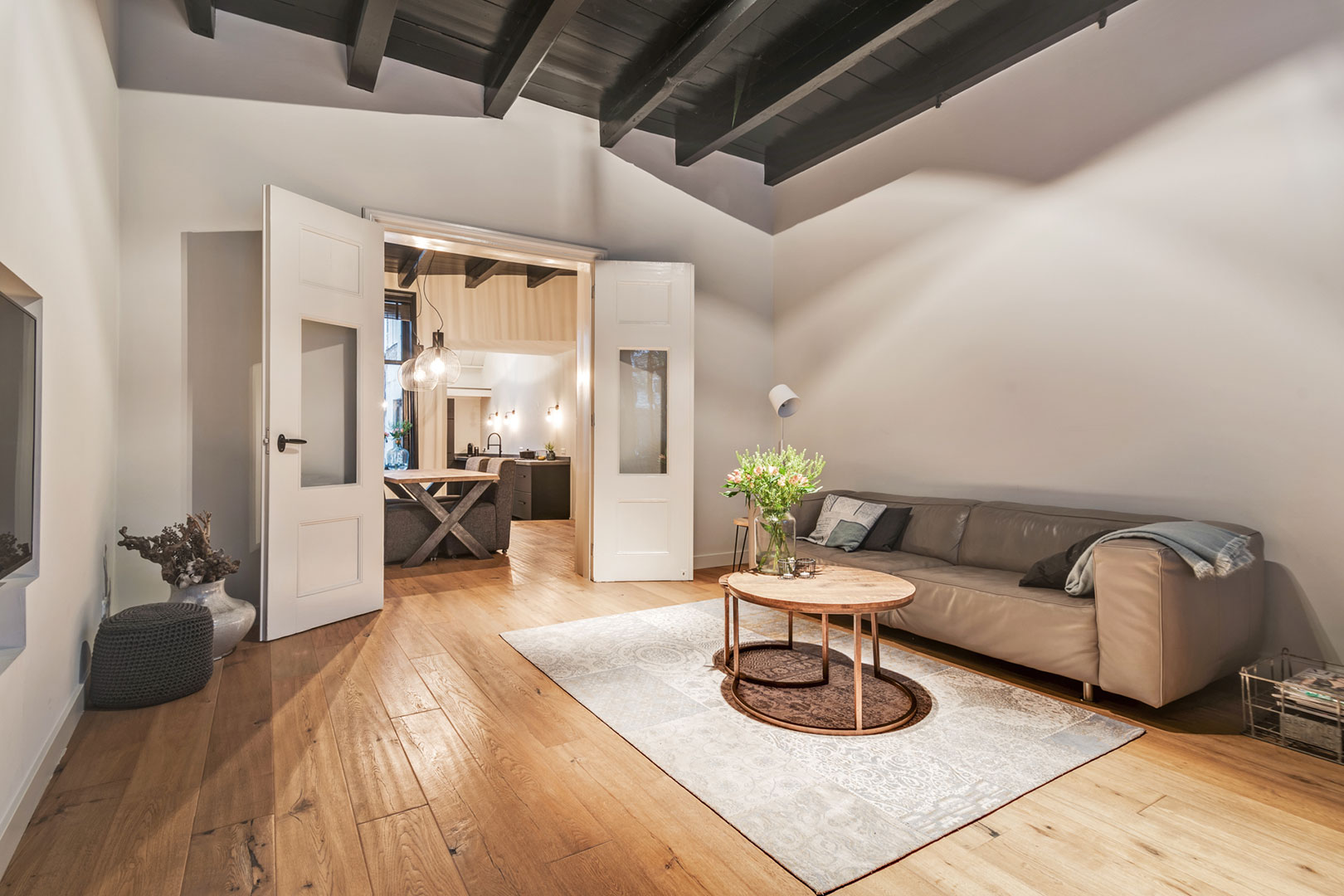 Living room with exposed ceiling beams and a bright seating area