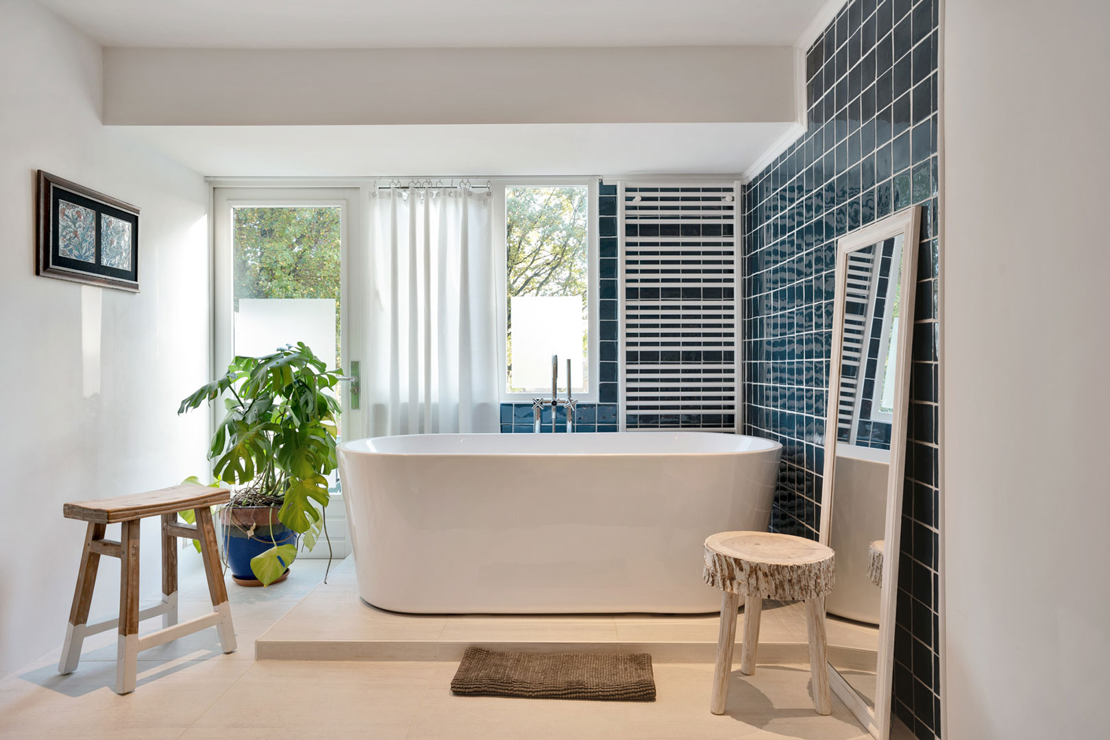 Bathroom with a freestanding bath by the window and dark wall tiles