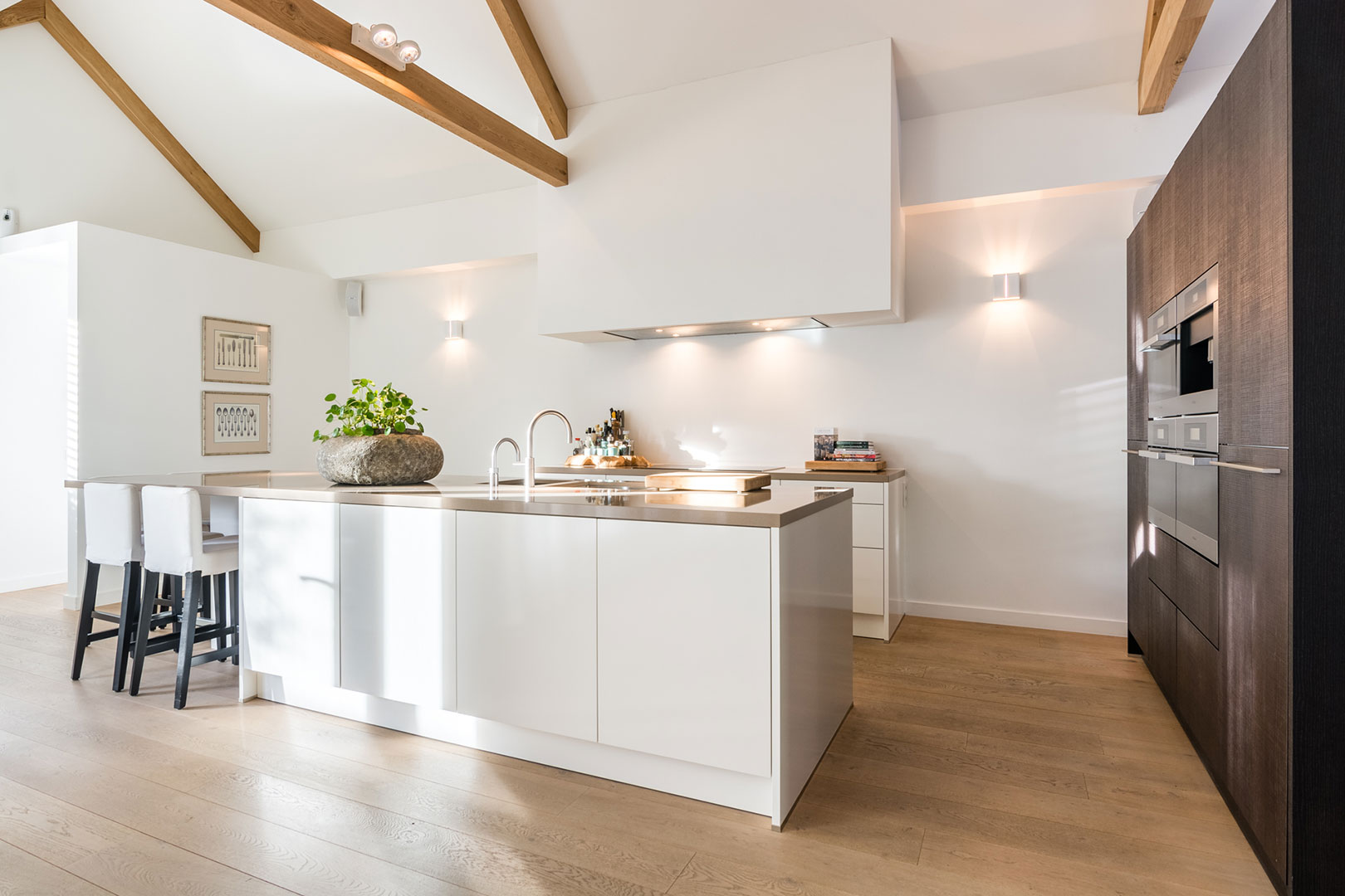 Bright kitchen with a clear white island and wooden ceiling beams
